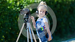 Child novice video blogger with a camera and a tripod.