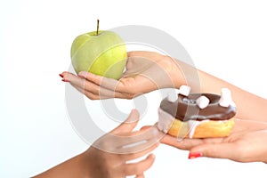 Child obesity concept with little girl hand choosing a sweet and unhealthy doughnut instead of a fruit photo