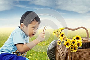 Child observe flowers with magnifying glass photo