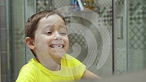A child without one tooth looks in the mirror and laughs. Happy childhood. Portrait of a cheerful boy. Kid mirror.