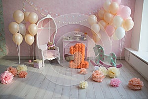 The child is one year old. room decorated with balloons with a gift cake, a toy horse and a large number one of colored