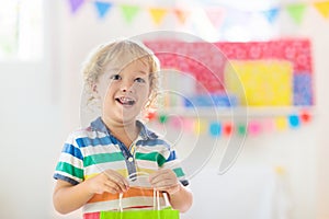 Child opening birthday present. Kid at party