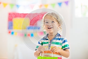 Child opening birthday present. Kid at party