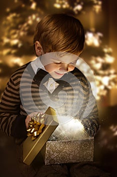 Child opening present box. Magic shining gift.