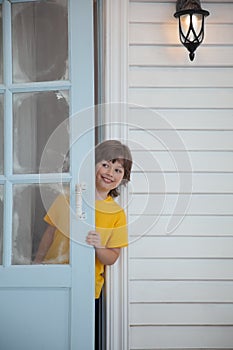 Child opens the door of a house in the village