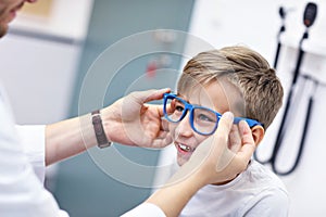 Child optometry male optometrist optician doctor examines eyesight of little boy photo