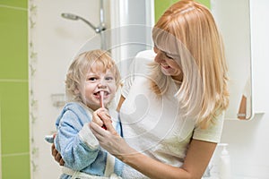 Child oral care. Mom is helping kid brush his teeth.