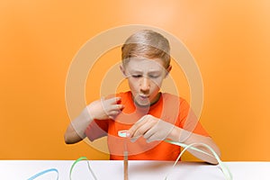 Child in an orange T shirt pricked his finger a quilling tool for twisting thin paper strips