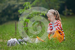 Child with orange water can outside watering just planted tree