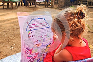 Child in an outdoor cafe reads the menu.