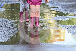 Child outdoor jump into puddle in boot after rain