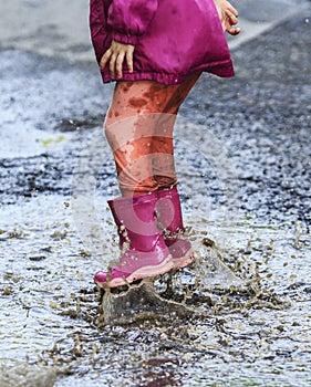 Child outdoor jump into puddle in boot after rain