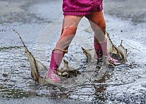 Child outdoor jump into puddle in boot after rain