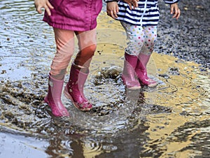 Child outdoor jump into puddle in boot after rain