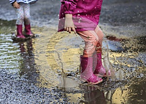 Child outdoor jump into puddle in boot after rain