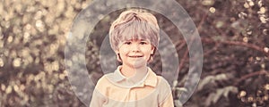 Child outdoors in nature. Happy child. Funny baby boy isolated on a background of green trees. Smiling child boy