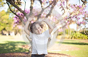 Child outdoors in a sunny day, happy put his hands up in the air