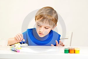 Child painting a ceramic pottery model at art class. Art school. Creative education and development. Child painting in the