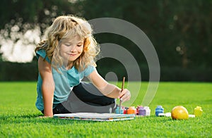 Child painting drawing art. Schooler kids drawing in summer park, painting art. Little painter draw pictures outdoor.