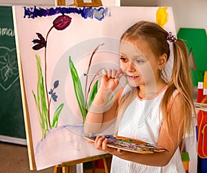 Child painting finger on easel. Group of kids with teacher.