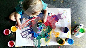 Child painting with paint brush at kindergarten using multi colored paints. Art therapy for children. Fun activities for toddlers