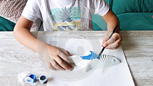 Child painting a plaster shark with a brush and blue tempera