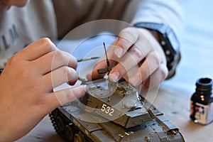 Child painting toy tank from World War 2