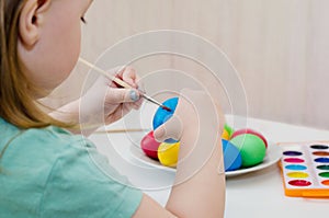 The child paints blue easter egg