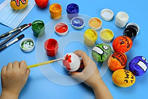 Child paints Easter eggs with colors, coronavirus theme