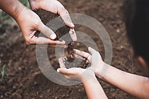 Child and parent holding soil and preparing soil for plant the tree