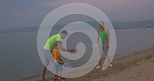 Child and parents playing tennis on the beach