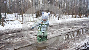 A child in the Park jumping on puddles. Splashes of water run up on the parties. Entertainment, outdoor sports. Early