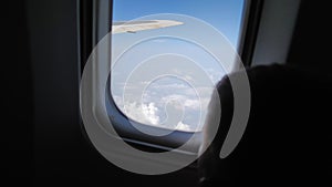 child passenger in an airplane flies with beautiful view outside the window, curious little boy strokes his finger on