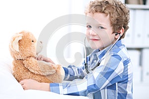 Child patient afrer health exam playing as a doctor with stethoscope and teddy bear