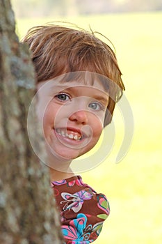 Child peeking from behind a tree