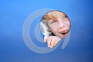 Child Peeking Through Hole at Playground