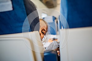 Child peeking between seats.Child sitting in front seat.Children on plane/bus/train rides.Children in transportation. Annoying kid