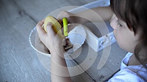 Child peels potatoes with a green peeler. preschooler prepares food. montessori materials for a lesson from the practical life zon