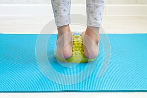 The child performs exercises on the green balancer from the valgus of the foot. The child& x27;s legs are close-up. Physical