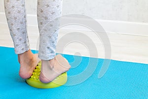 The child performs exercises on the green balancer from the valgus of the foot. The child& x27;s legs are close-up. Physical