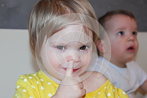 The child is picking his nose. A little girl, a bad habit. Picking in the nose.