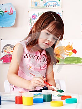 Child with picture and brush in play room.