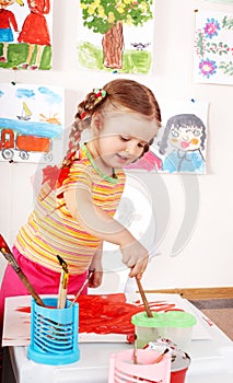 Child with picture and brush in playroom.