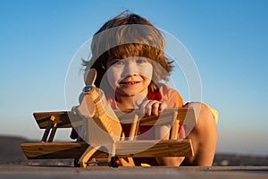 Child pilot aviator with kids airplane dreams of traveling in summer in nature.