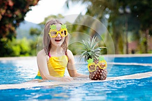 Child with pineapple in swimming pool. Kids swim