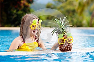 Child with pineapple in swimming pool. Kids swim