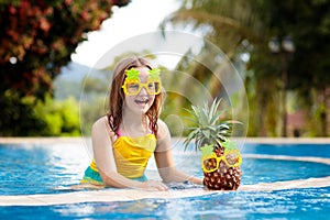 Child with pineapple in swimming pool. Kids swim