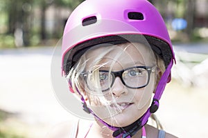 Child with pink bicycle helmet and black glasses