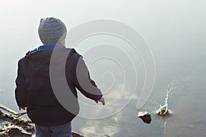 Child pitched a stone into the water photo