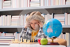 Child play chess in classroom at school. Clever concentrated and thinking child playing chess. Child boy developing